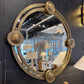 Decorative round mirror with gold frame on a dark tiled wall