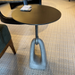 Small round table with a unique base design on a textured floor.