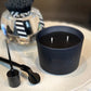 Black candle with wick trimmer on a textured surface