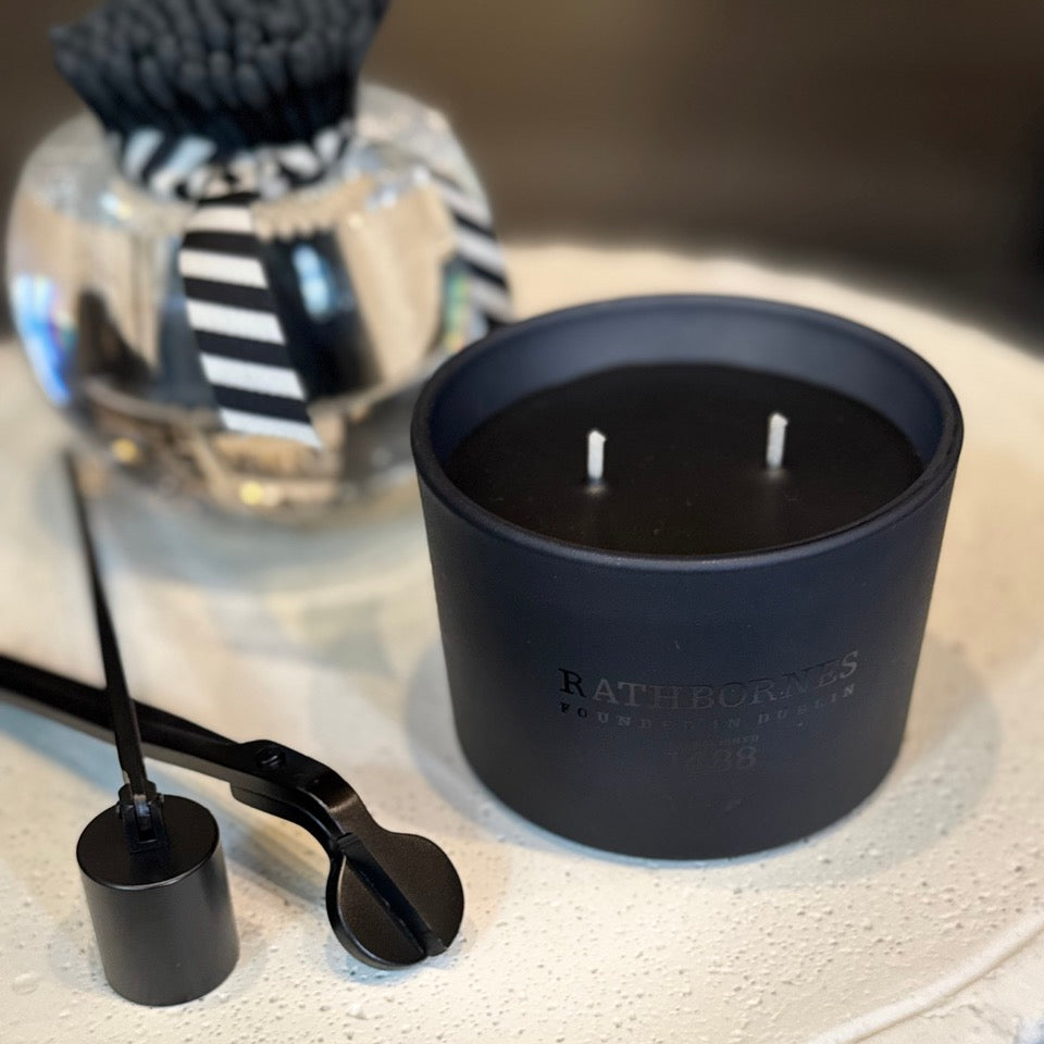 Black candle with wick trimmer on a textured surface