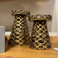 Two ornate brass candle holders on a wooden surface with a neutral background.