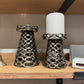 Decorative metal candle holders with a white candle on a wooden surface.