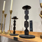 Set of candlesticks including gold, black, and bronze designs on a wooden surface.
