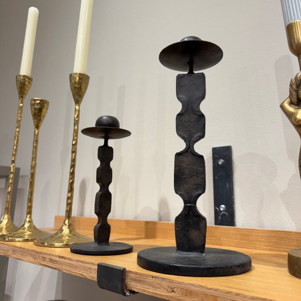 Set of candlesticks including gold, black, and bronze designs on a wooden surface.