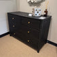 Black woven dresser with decorative items in a room setting