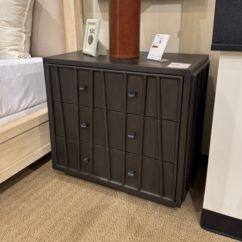 Dark wooden nightstand with a lamp on top in a bedroom setting