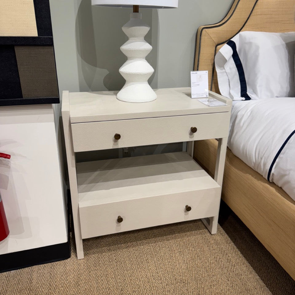 White nightstand with a lamp next to a bed in a bedroom setting
