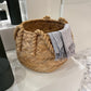 Woven basket with a striped towel on a tiled floor