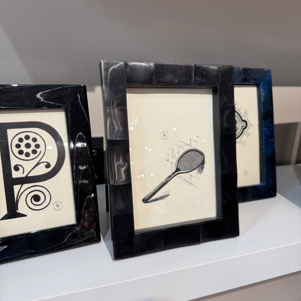 Three black-framed pictures on a white surface with a neutral background