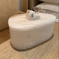 Marble-like stone with a small crystal on top, placed on a wooden surface.