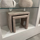Set of textured stools and a small table on a white platform with a glass surface.