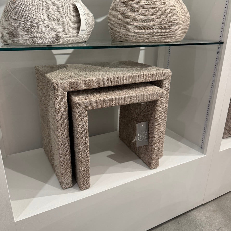 Set of textured stools and a small table on a white platform with a glass surface.