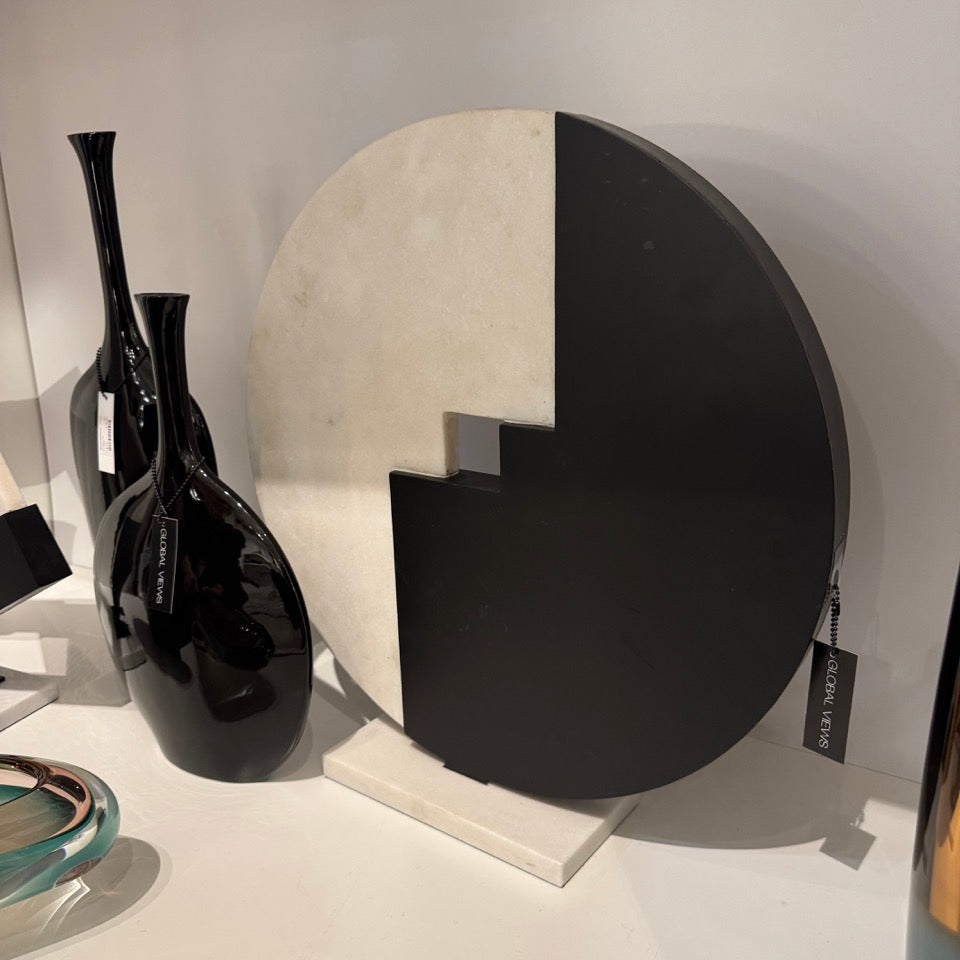 Decorative wall piece with black and white design on a white surface