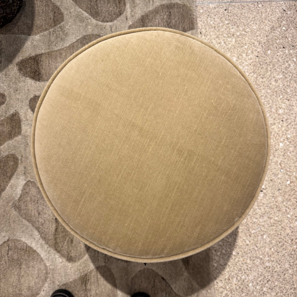 Round beige stool on a patterned carpet