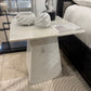 White marble side table in a room setting with a bed and decor items.