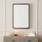 Rectangular mirror with decorative frame above a striped dresser.