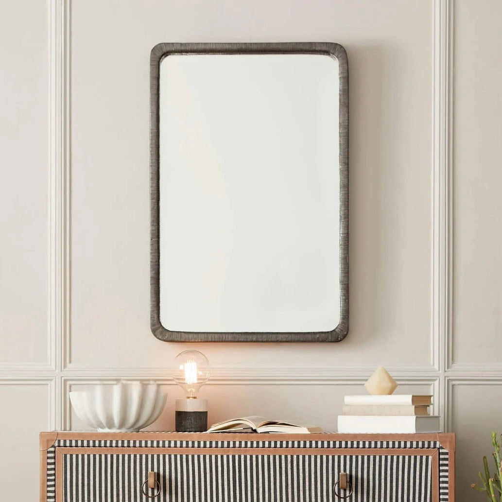 Rectangular mirror with decorative frame above a striped dresser.