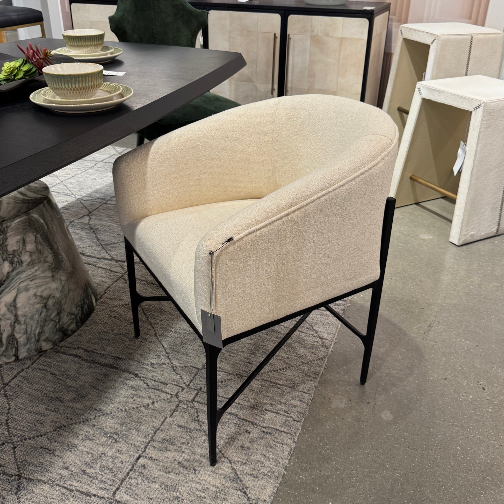 Beige armchair in a room with a dining table and decor items.