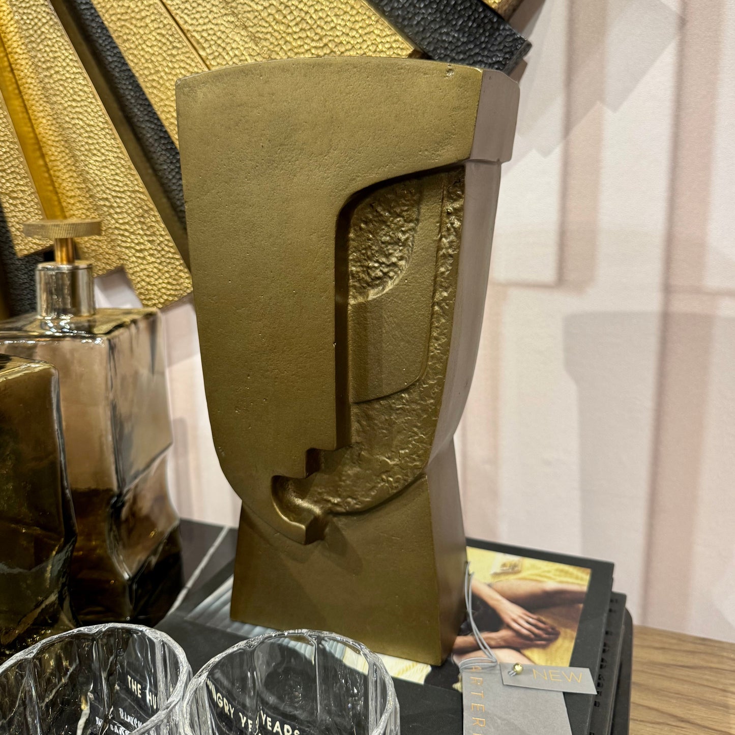Decorative sculpture on a table with glasses and books in the background