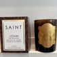 Candle and packaging with 'Saint' branding on a white surface