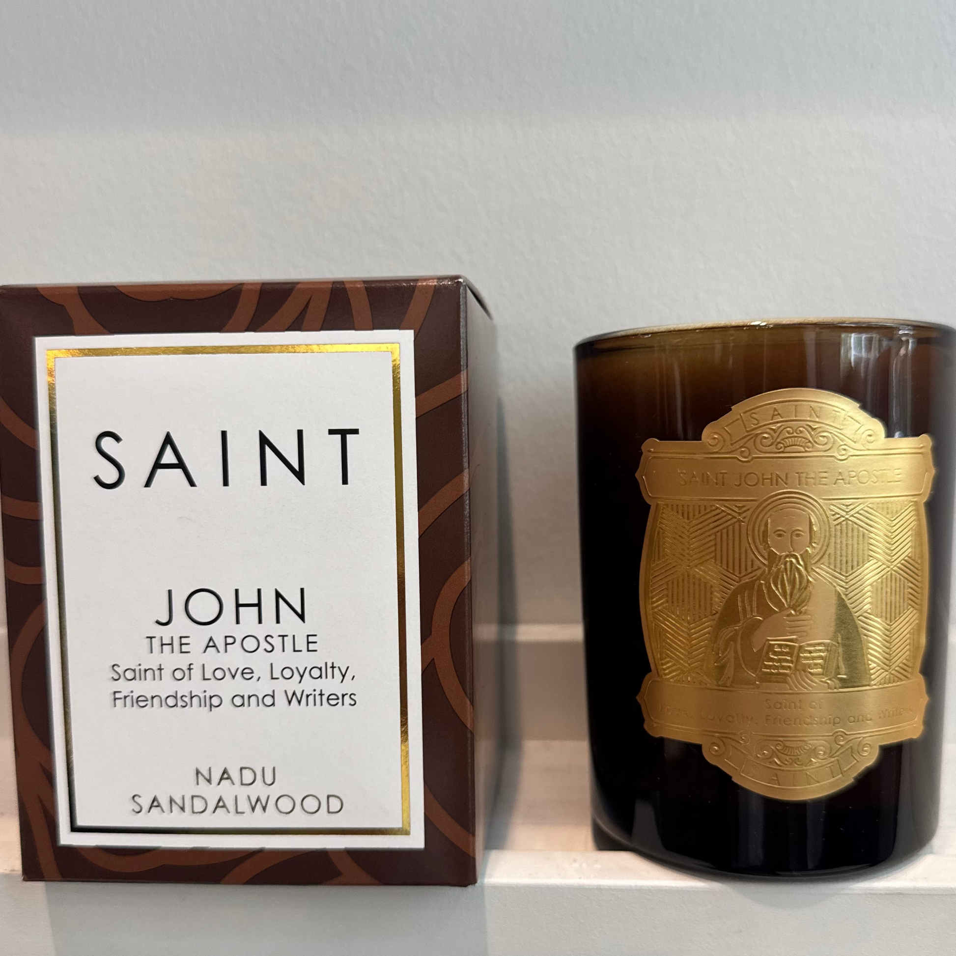Candle and packaging with 'Saint' branding on a white surface