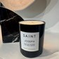 Black candle with a white label on a light surface, with a marble object in the background.