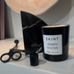 Black candle labeled 'Saint Joseph' on a shelf with decorative items.