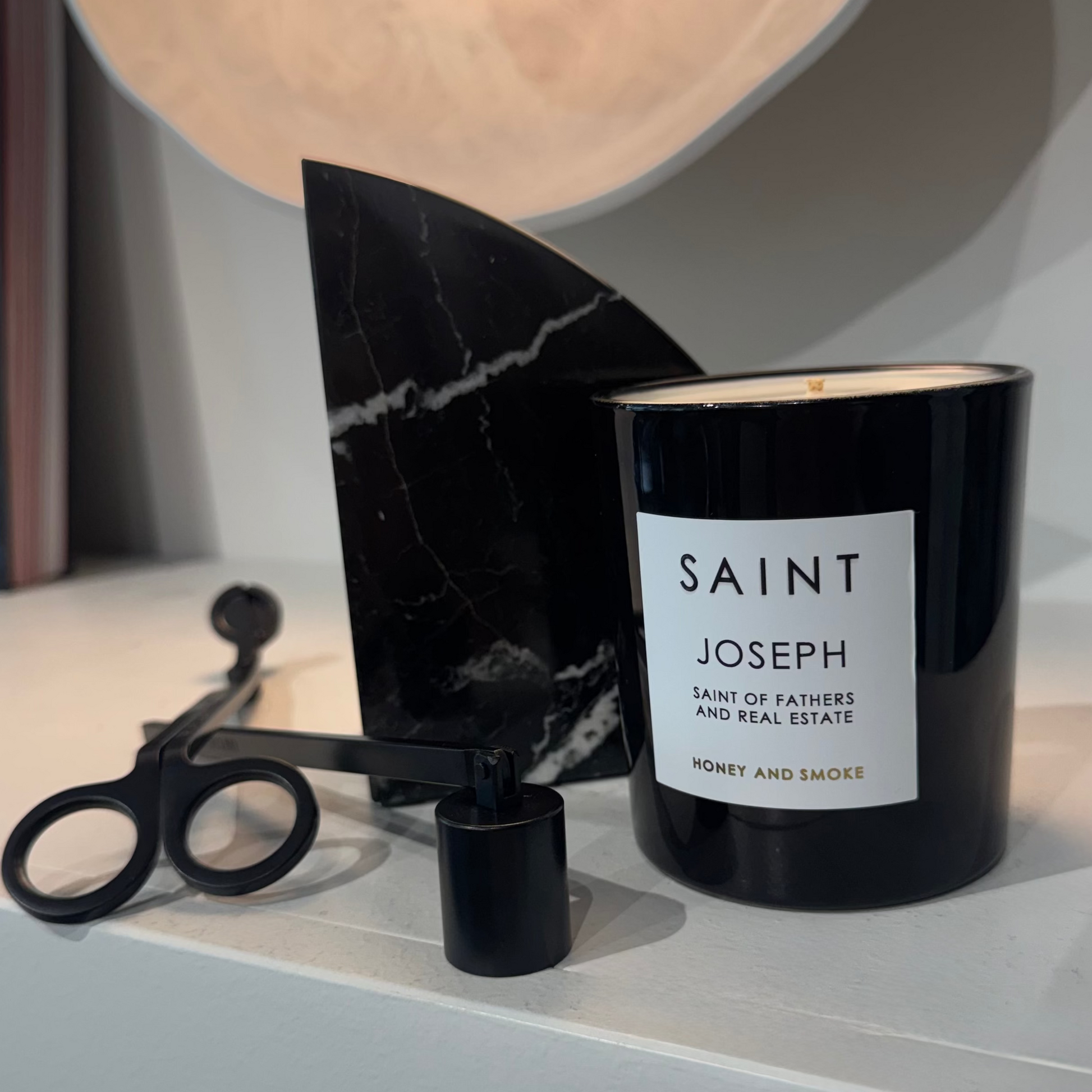 Black candle labeled 'Saint Joseph' on a shelf with decorative items.