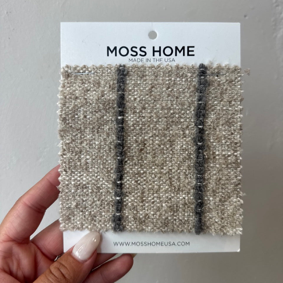 Moss Home carpet sample card held by a hand against a gray background