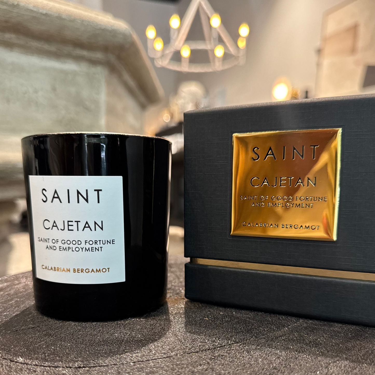 Black candle labeled 'Saint Cajetan' next to its packaging on a reflective surface.