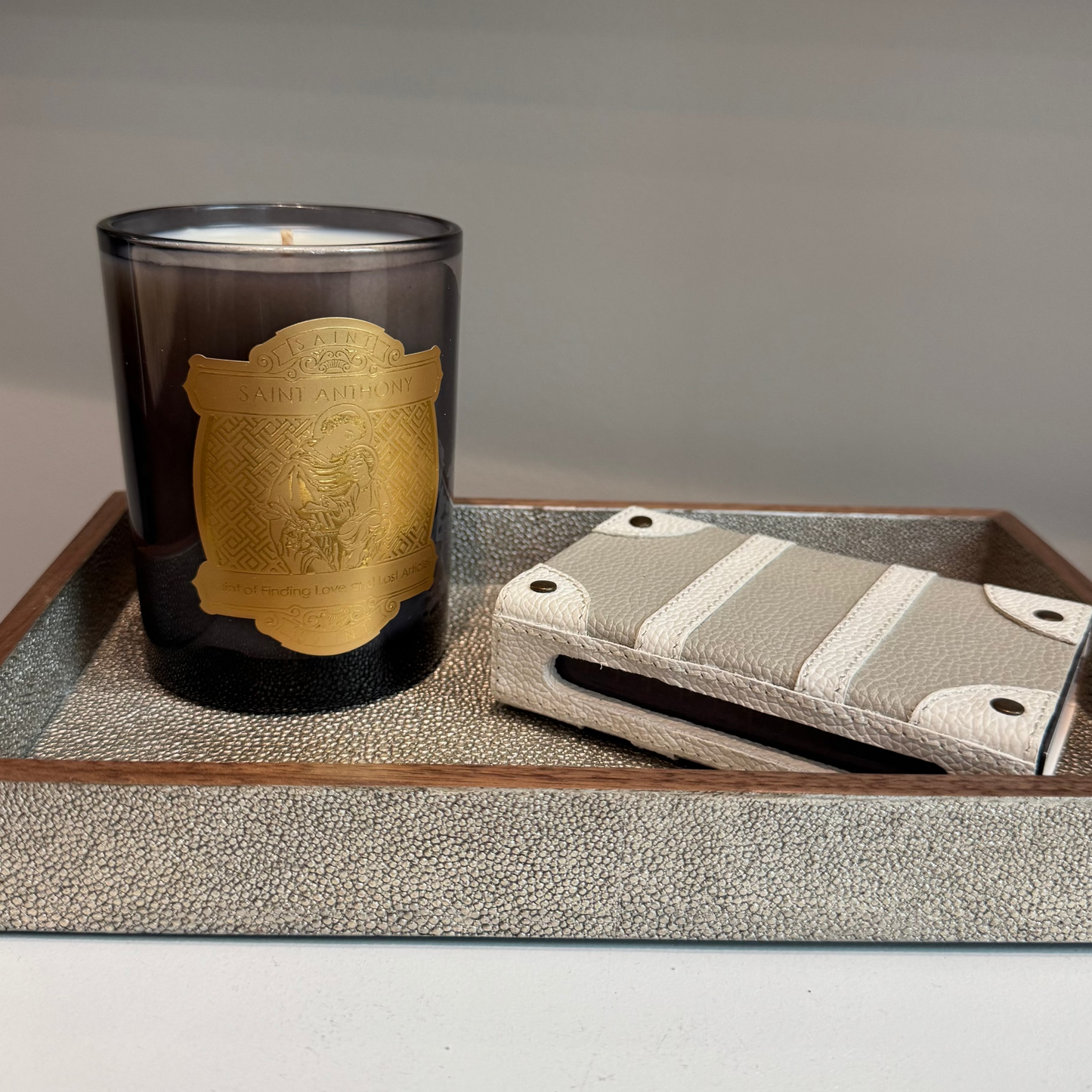 Candle with gold label and small pouch on a textured tray