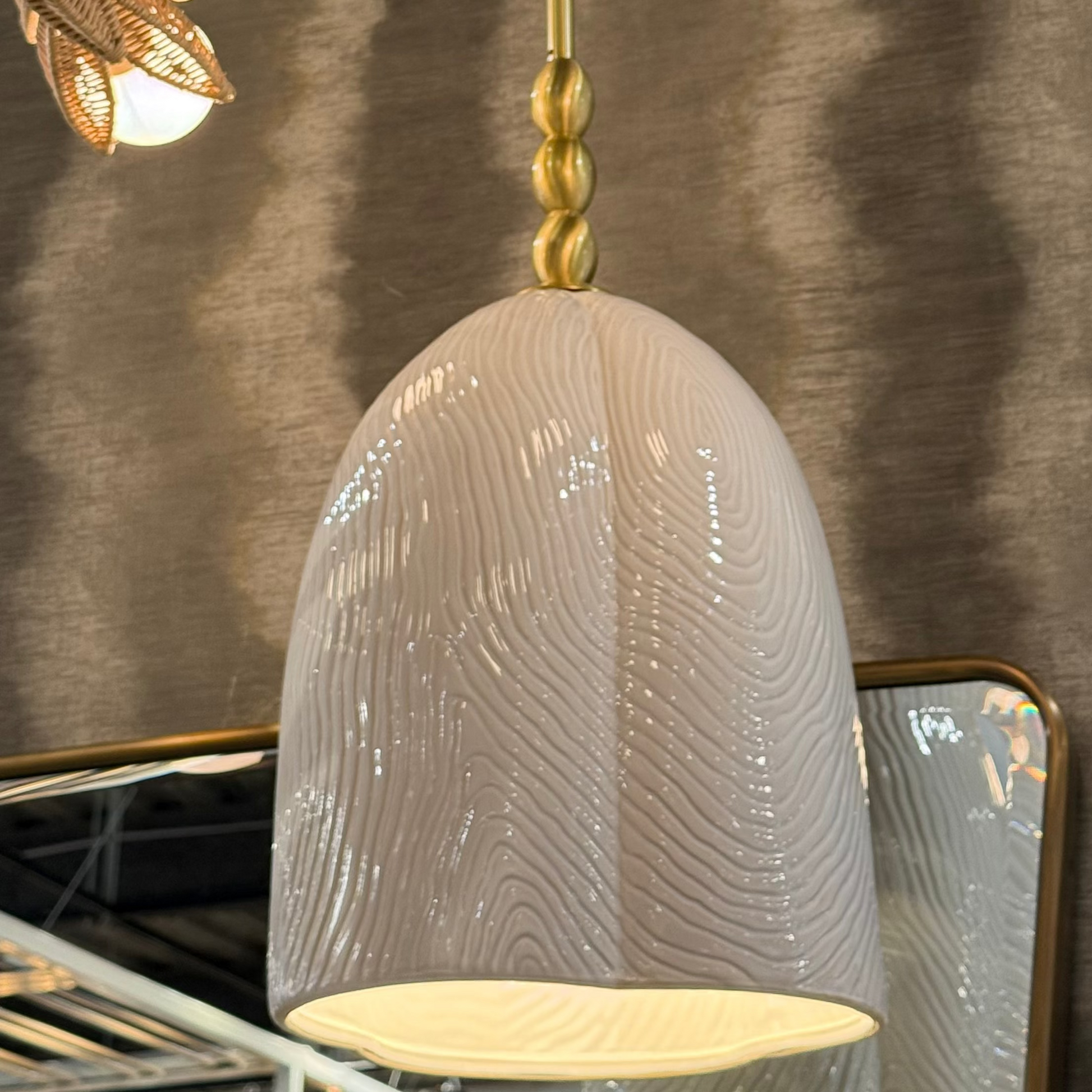 Textured pendant light with gold fixture against a neutral background