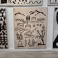 Decorative wall art with black line drawings on a beige background, displayed among other artworks.
