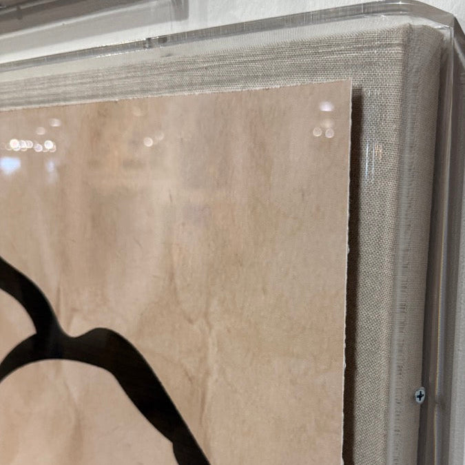 Close-up of a framed artwork with abstract design and text on a white background