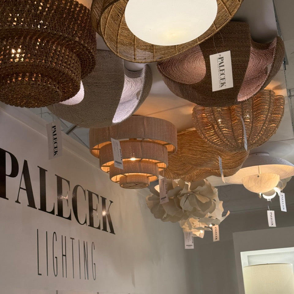 Wicker chandeliers hanging above a Palecek Lighting display.