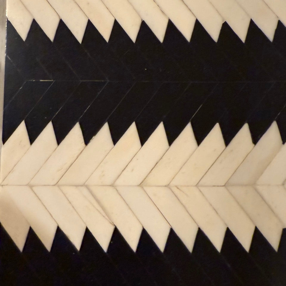 Pattern of black and white chevron shapes on a textured surface