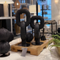 Decorative black cactus sculptures on a wooden stand with a blurred interior background