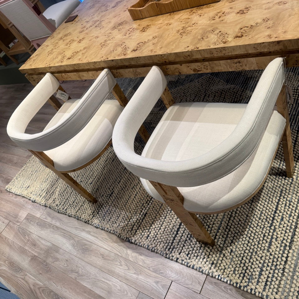 White chairs around a wooden dining table with a rug on the floor.