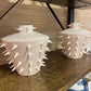 Two white ceramic vases with spiky texture on a wooden surface.