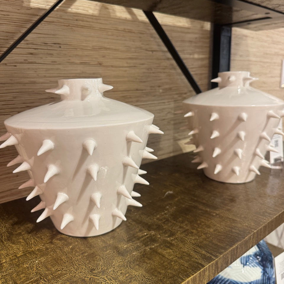 Two white ceramic vases with spiky texture on a wooden surface.