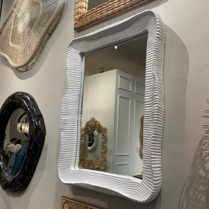 Collection of decorative mirrors with unique frames on a wall.