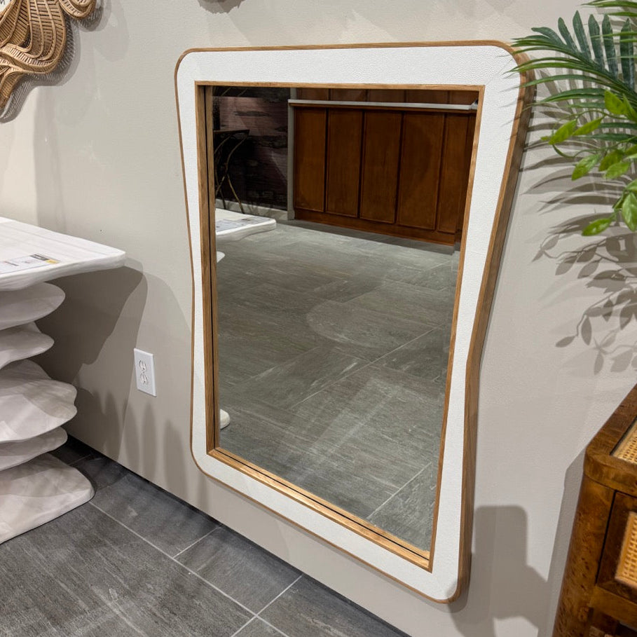 Rectangular mirror with a wooden frame on a wall in a room with a plant and other decor items.