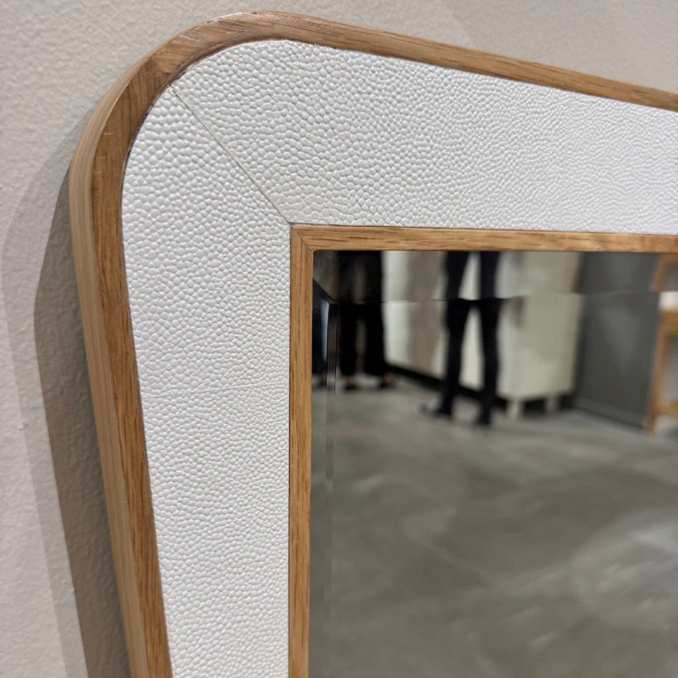 Mirror with a textured white frame on a neutral wall