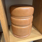 Stack of brown leather ottomans on a wooden shelf