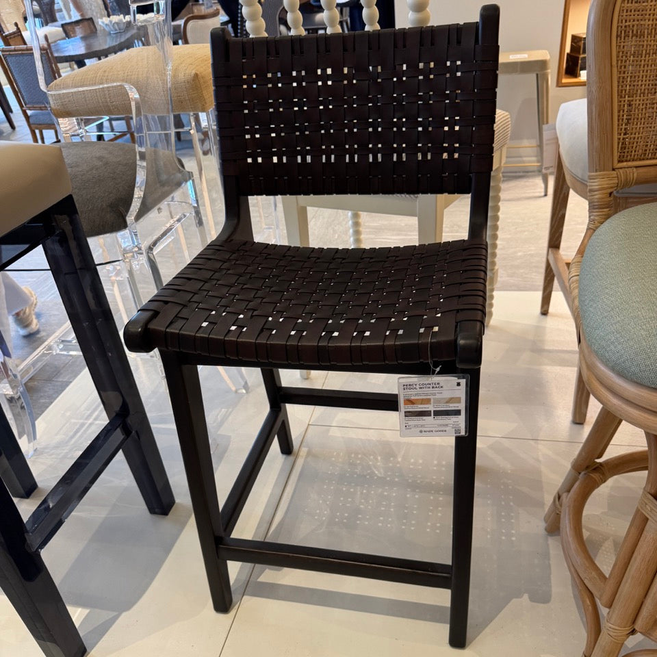 Black woven chair in a showroom setting with other furniture.
