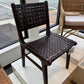 Dark woven chair on display in a store setting with another chair and table in the background.