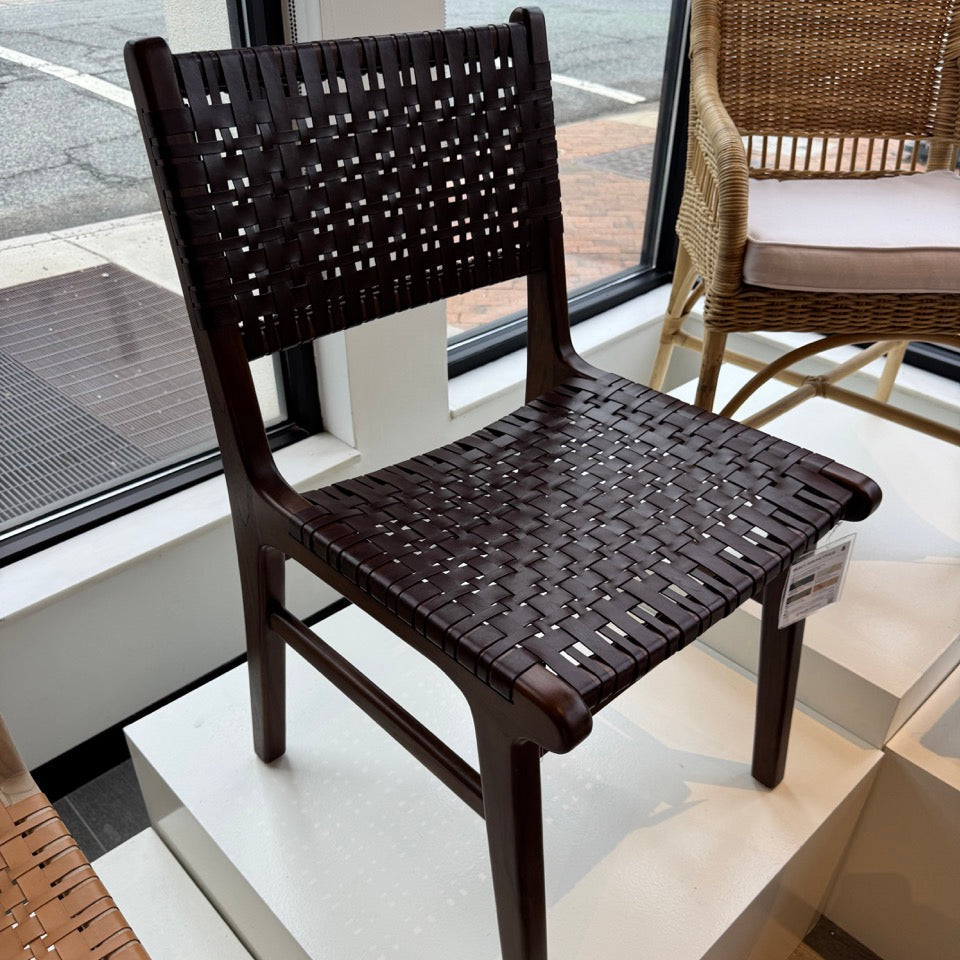 Dark woven chair on display in a store setting with another chair and table in the background.