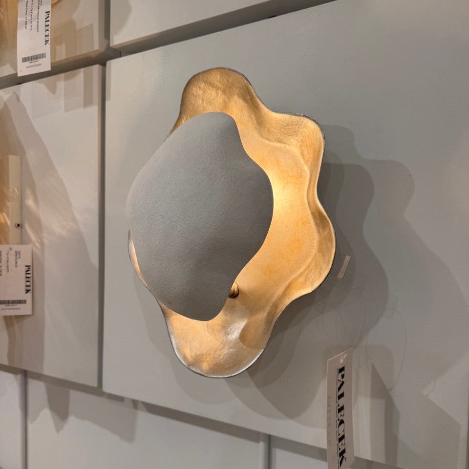 Decorative wall sconce with gold and gray design on a display cabinet.