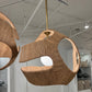 Woven pendant light fixture hanging in a room with a chair and decor.