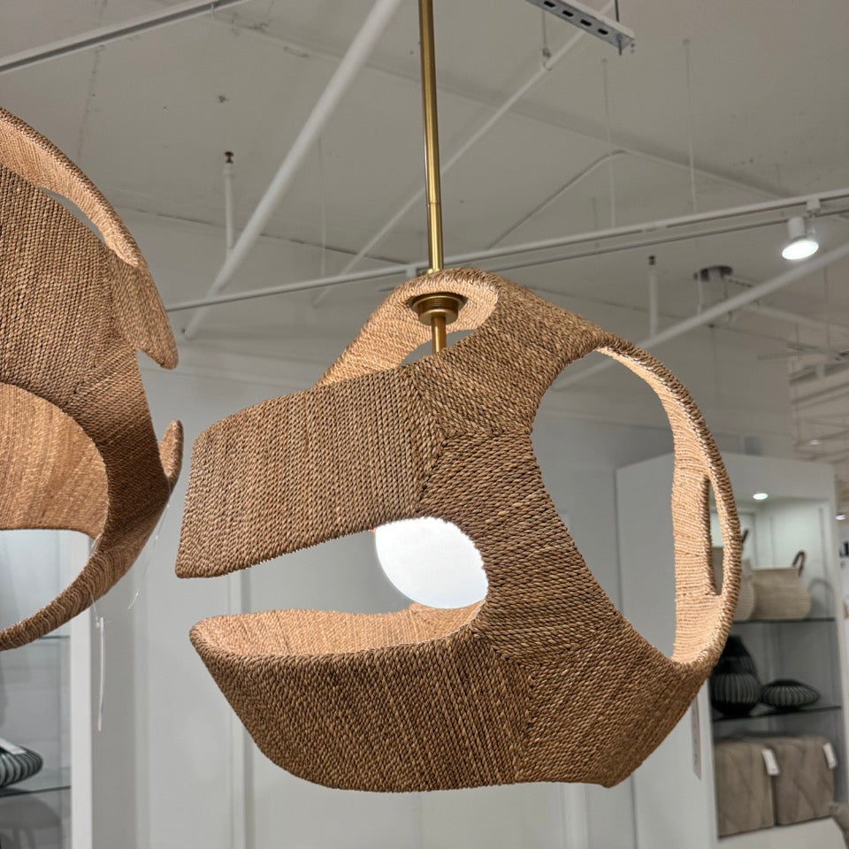 Woven pendant light fixture hanging in a room with a chair and decor.